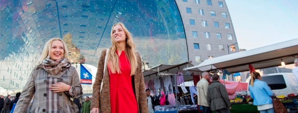 Twee vrouwen lachend op de markt bij Blaak voor de markthal.