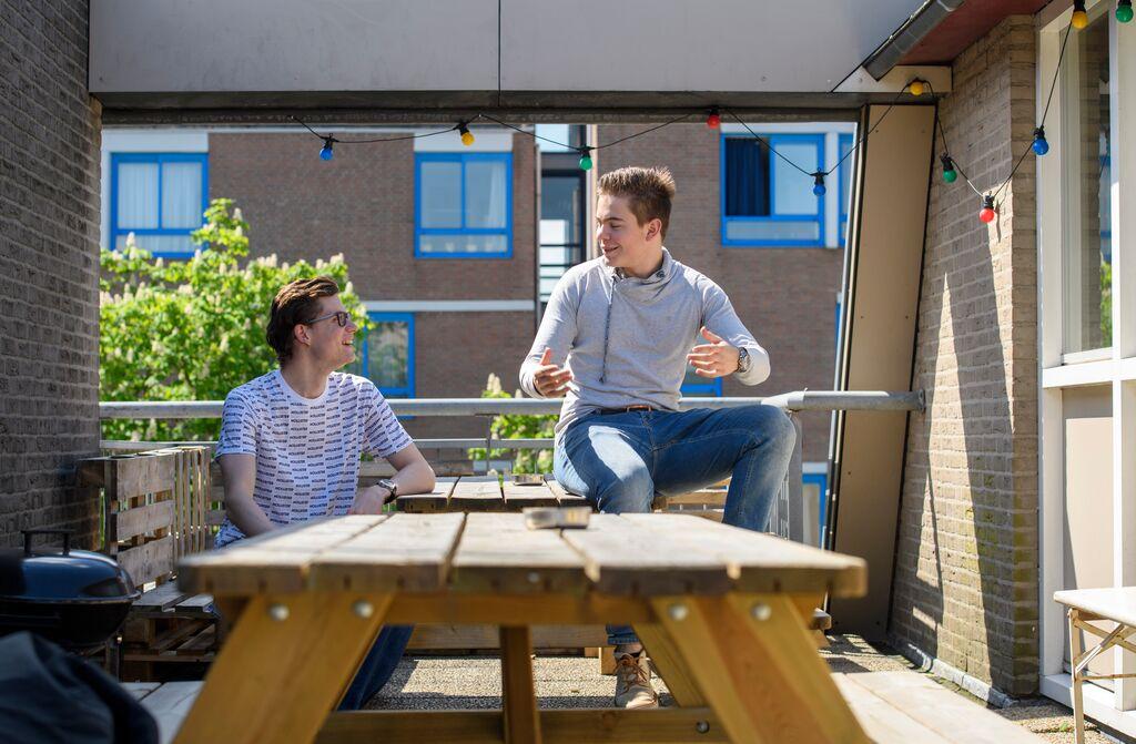 twee studenten op het balkon aan het praten